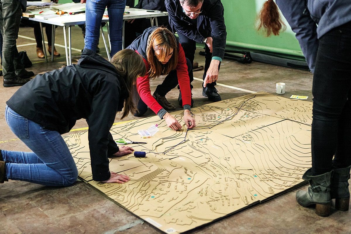 People in coats on their knees leaning over a large map.jpg